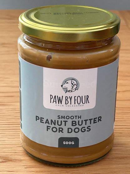 Jar of Paw by Four peanut butter for dogs on a wooden surface
